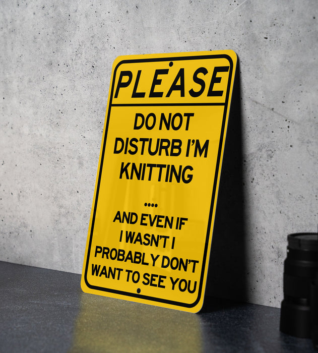 a yellow sign that says please don't disturb i'm knitting and even