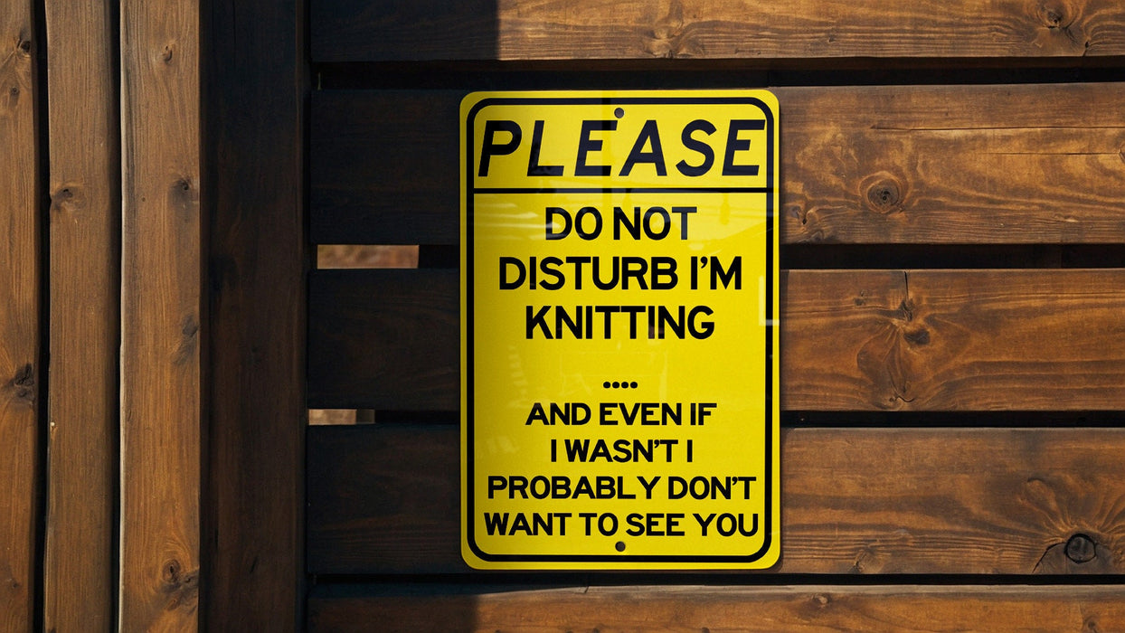 a yellow don't disturb im knitting sign on a wooden fence