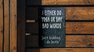 a sign on a wooden fence that says either do yoga or say bad words