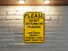 a yellow sign on a brick wall that says please do not disturb i'm