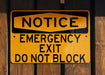 a do not block exit sign on a wooden fence