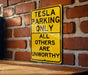a yellow sign on a brick wall that says tesla parking only all others are un