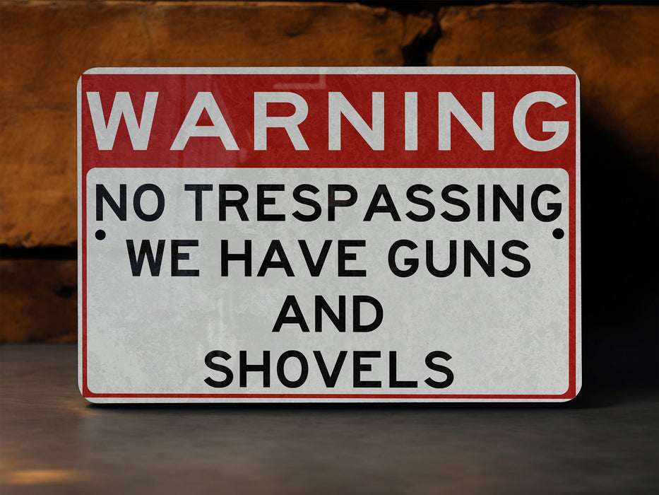 a red and white warning sign stating no trespassing we have guns and shovel