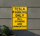 a yellow sign that says tesla parking only all others are unworthyly