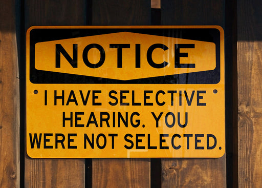 a yellow and black sign on a wooden fence
