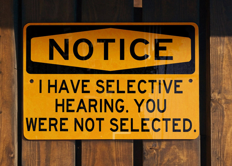 a yellow and black sign on a wooden fence