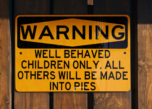 a yellow and black sign on a wooden fence