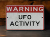 a red and white sign that says warning of ufo activity