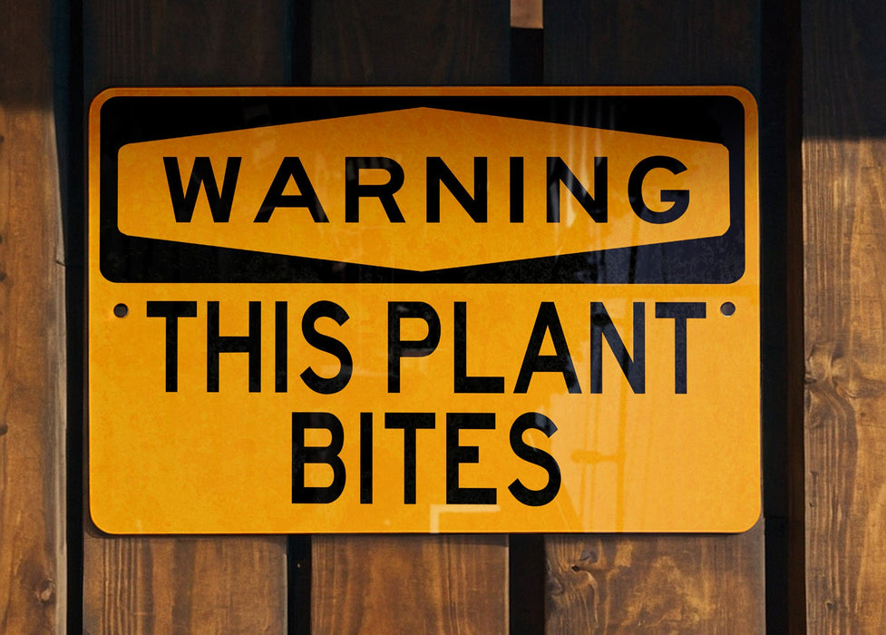 a yellow and black sign on a wooden fence