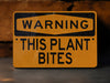 a yellow warning sign that says warning this plant bites