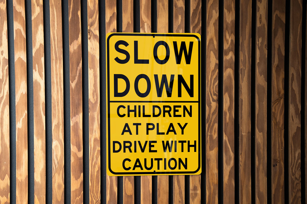 a yellow slow down sign on a wooden wall