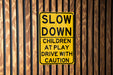 a yellow slow down sign on a wooden wall