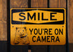 a yellow sign that says smile you're on camera