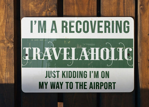 a green and white sign that says i'm a recovering travelaholic