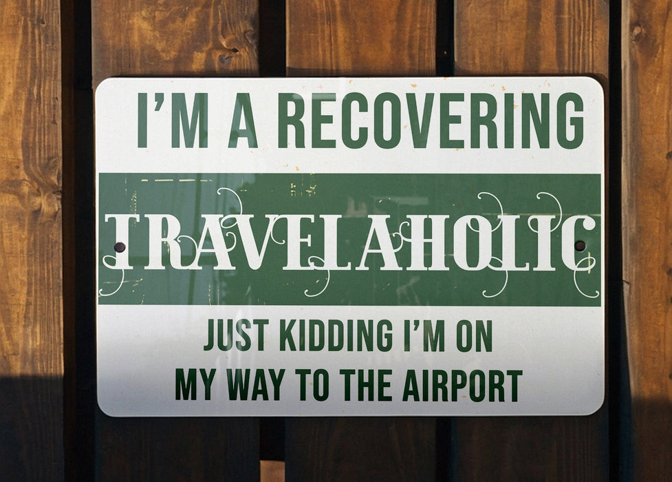 a green and white sign that says i'm a recovering travelaholic
