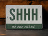 a green and white sign that says shh no one cares