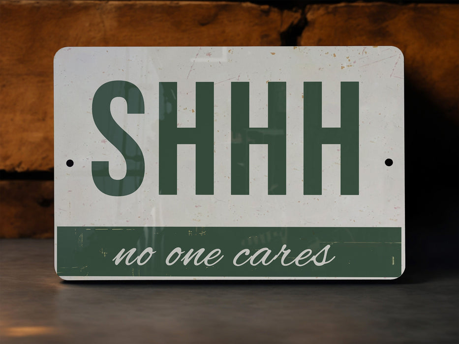 a green and white sign that says shh no one cares