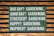 a green sign on a wooden bench that says, bad day gardening good day gardening