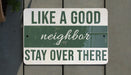 a green and white sign that says like a good neighbor stay over there