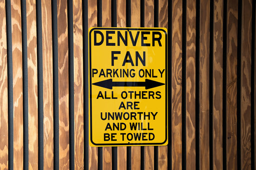 a yellow sign on a wooden fence that says denver fan parking only all others are