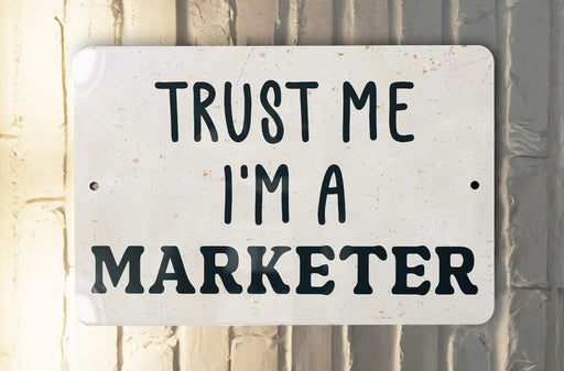 a white sign that says trust me i'm a marketer