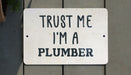 a white sign that says trust me i'm a plumber
