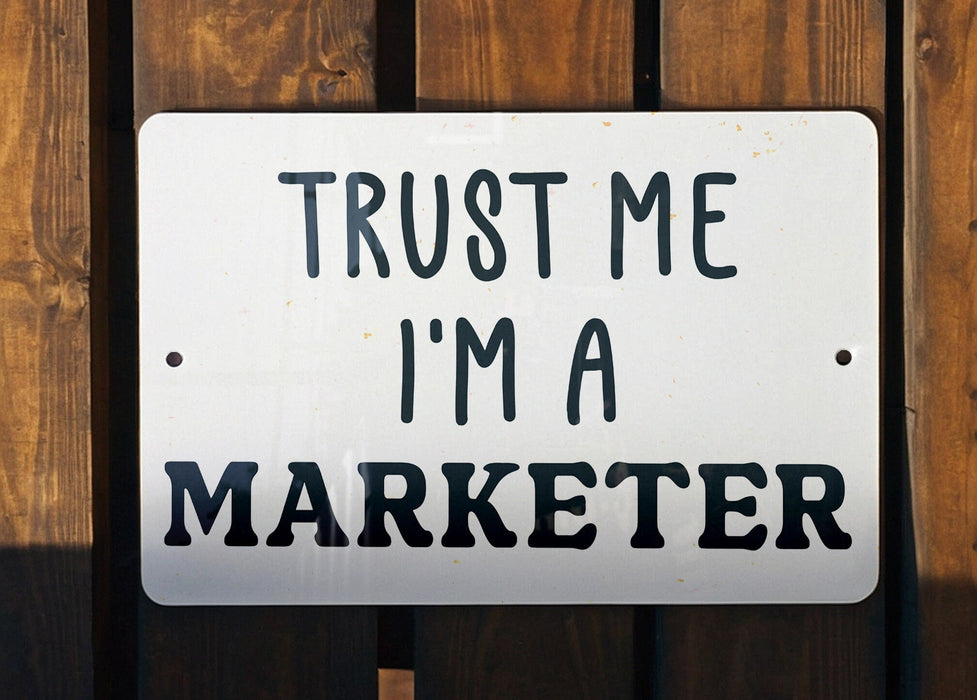 a white sign that says trust me i'm a marketer