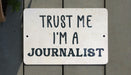 a white sign that says trust me i'm a journalist