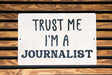 a white sign that says trust me i'm a journalist