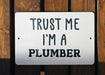 a white sign that says trust me i'm a plumber