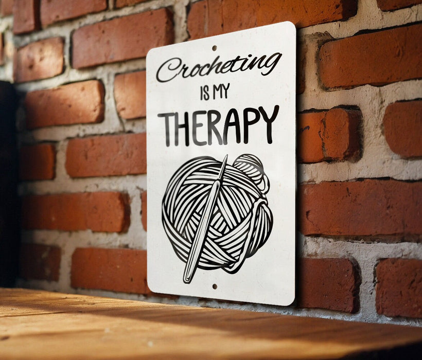 a sign on a brick wall that says crocheting is my therapy