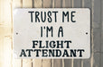 a white sign that says trust me i'm a flight attendant