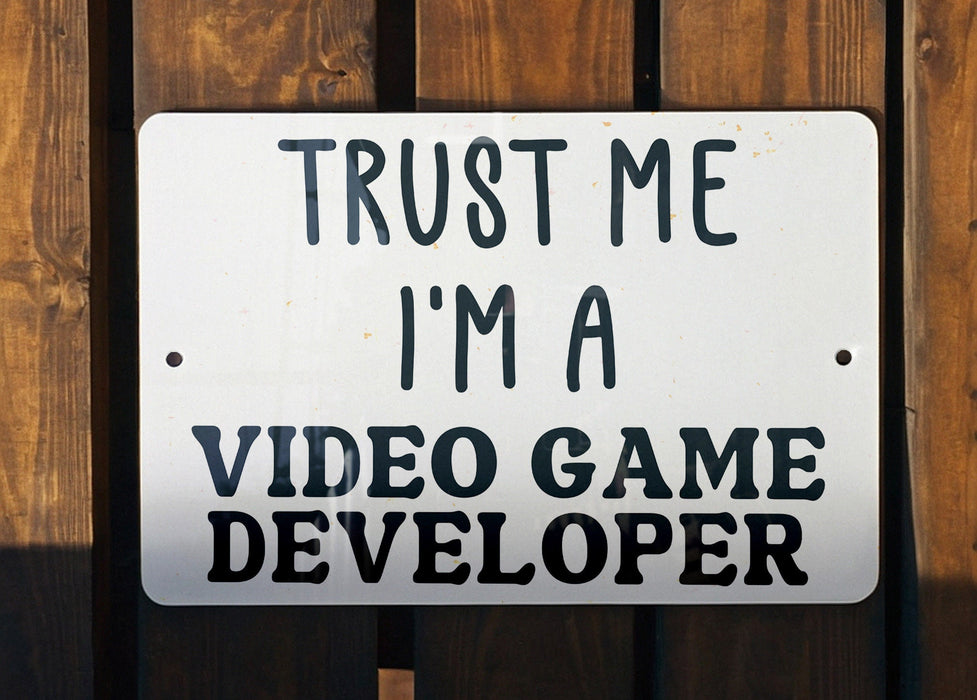 a white sign that says trust me i'm a video game developer