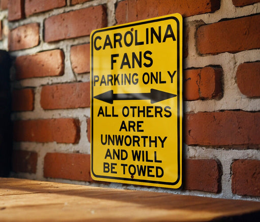 a yellow sign on a brick wall that says, carolina fans parking only all others