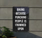 a sign on the side of a building that says biking because punching people is frown