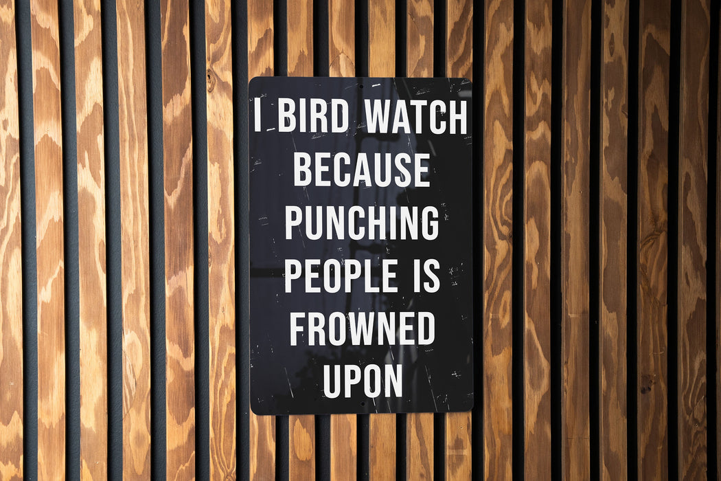 a sign on a wooden wall that says, i bird watch because punching people is