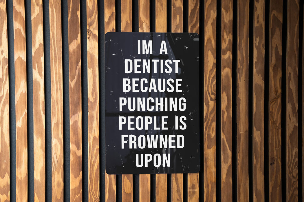 a sign on a wooden wall that says i'm a dentist because punching people