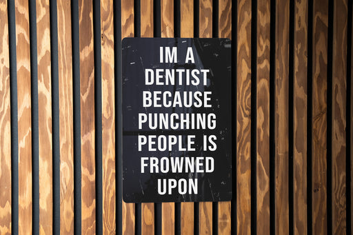 a sign on a wooden wall that says i'm a dentist because punching people