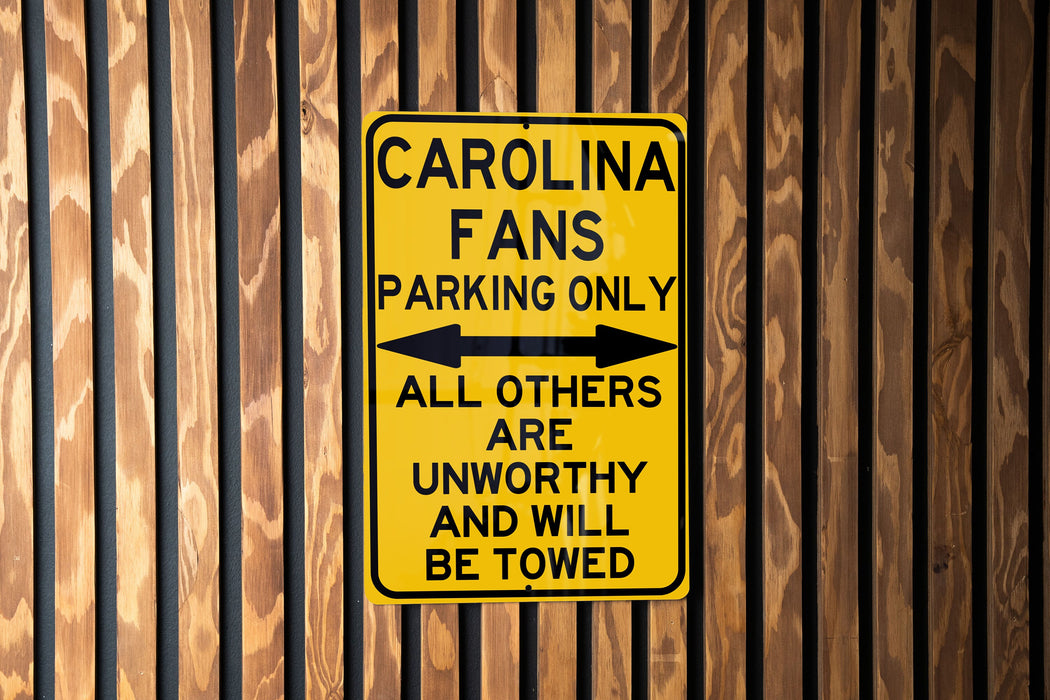 a yellow parking only sign on a wooden fence
