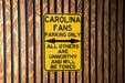 a yellow parking only sign on a wooden fence