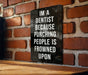 a sign on a brick wall that says i'm a dentist because punching people