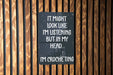 a sign on a wooden wall that says it might look like i'm listening