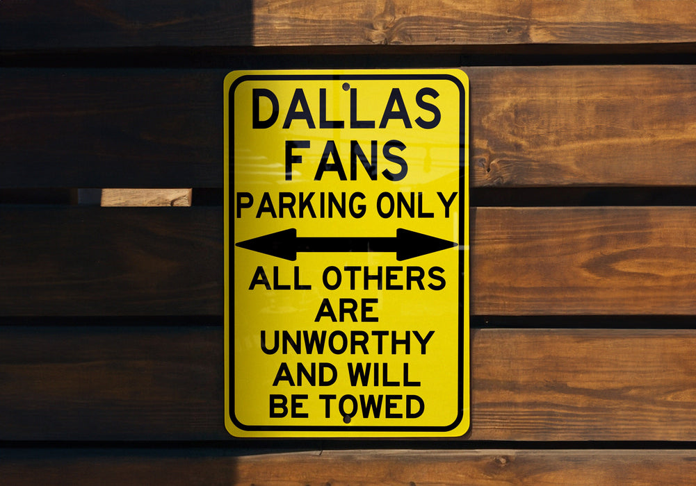 a yellow sign on a wooden wall that says dallas fans parking only all others