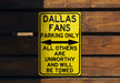 a yellow sign on a wooden wall that says dallas fans parking only all others