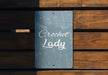 a sign that reads crochet lady on a wooden bench