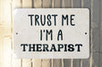 a white sign that says trust me i'm a therapist