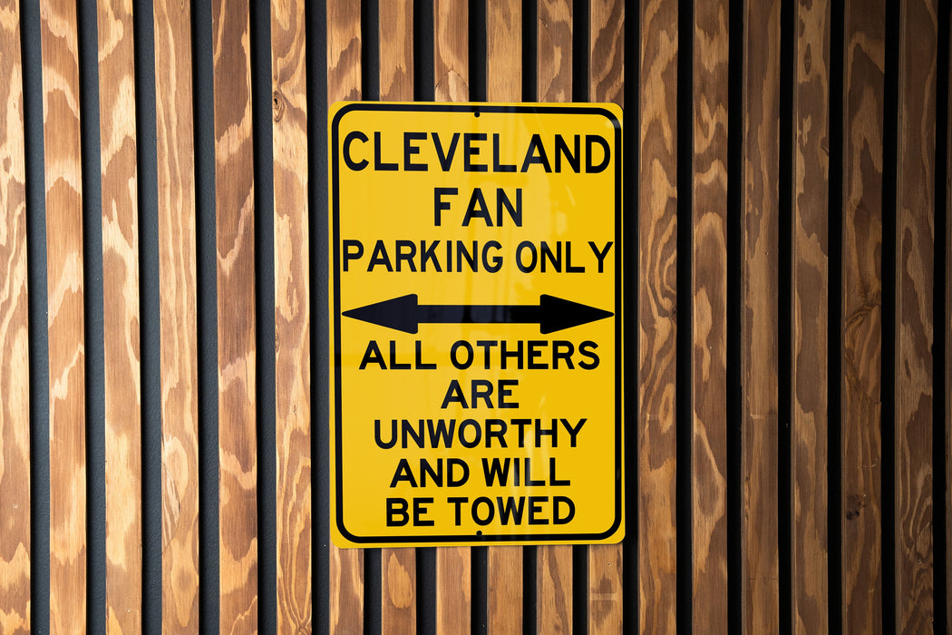 a yellow and black sign on a wooden fence