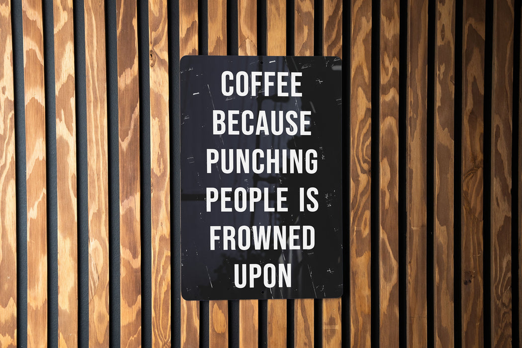 a sign on a wooden wall that says coffee because punching people is frowned upon