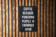 a sign on a wooden wall that says coffee because punching people is frowned upon