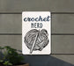 a sign that says crochet nerd next to a potted plant